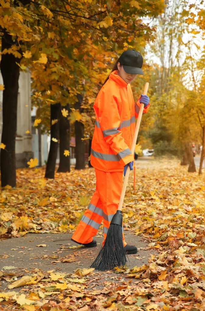 street cleaner sweeping fallen leaves outdoors on autumn day